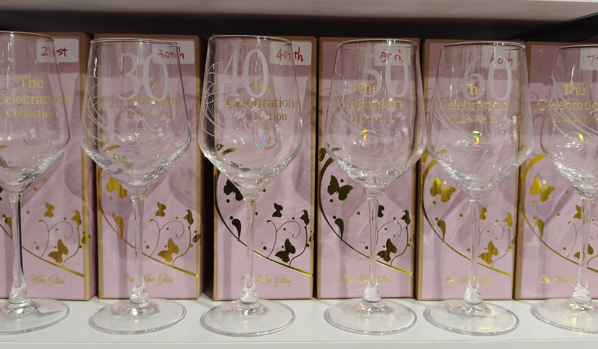 Row of milestone birthday wine glasses in pink gift boxes