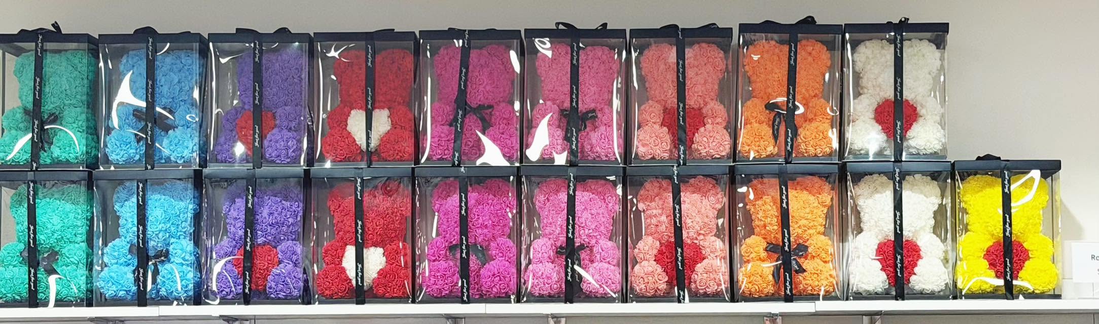 Shelves of colourful rose-flower gift bears in clear display boxes